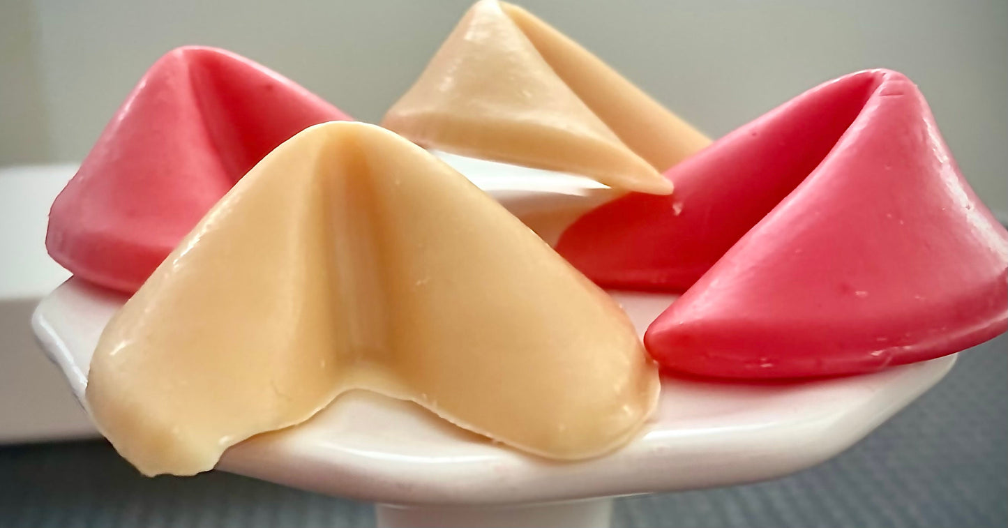 wax shapes that look like fortune cookies. 2 are tan and 2 are pink on a white stand