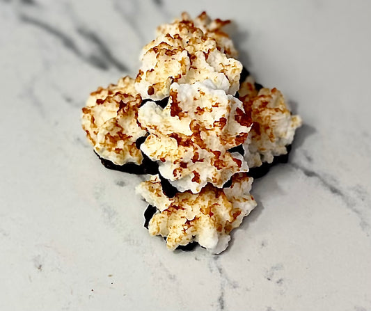 A cluster of white and black wax tarts designed to resemble coconut macaroons, placed on a marble surface.